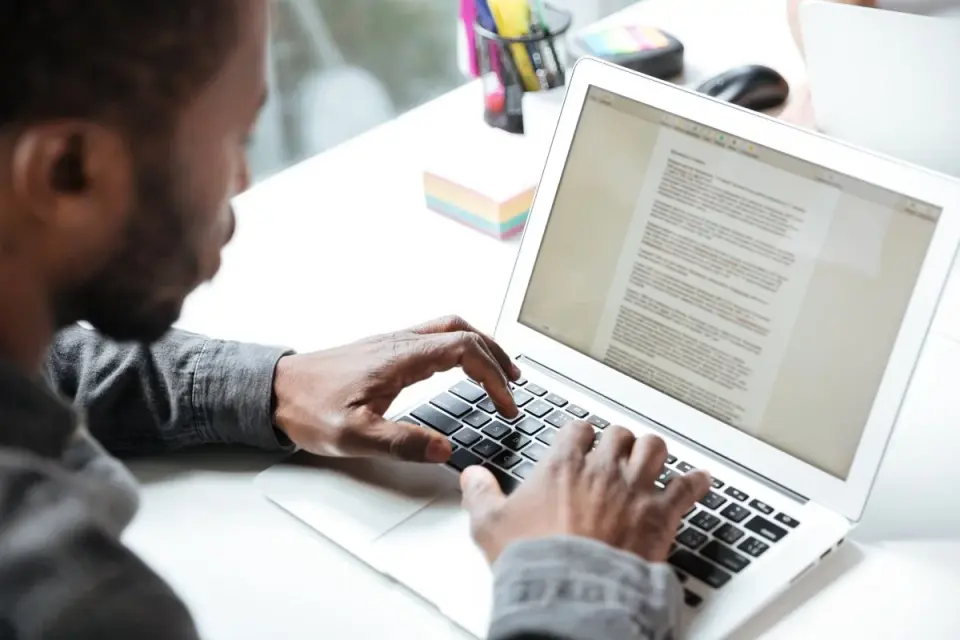man typing to his laptop writing something