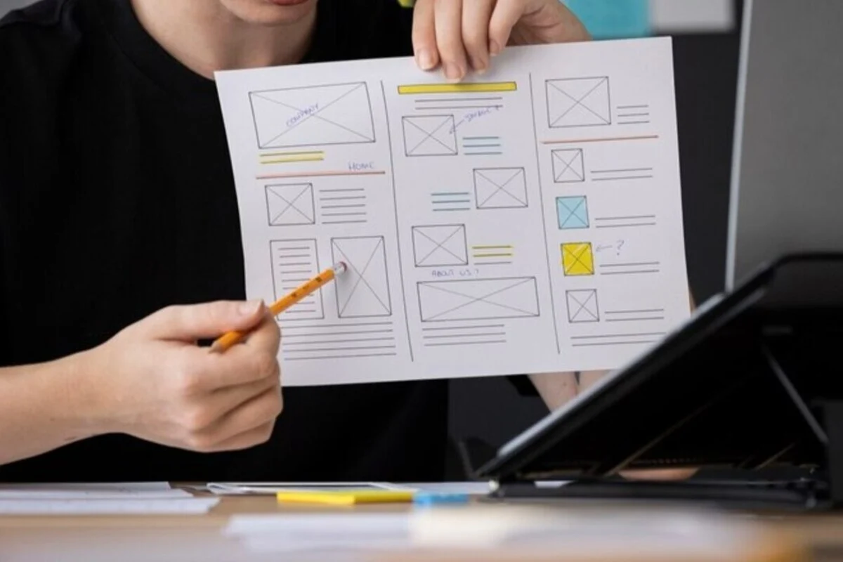 Seorang Perempuan Menunjukkan Sketsa Web Design dengan Mempertimbangkan User Scenario